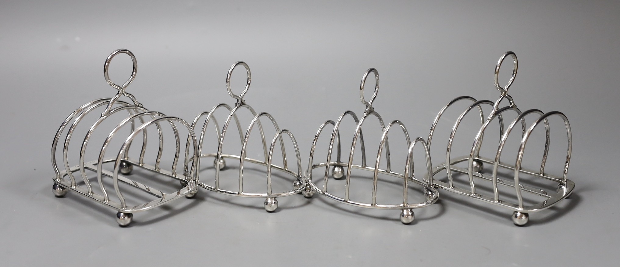 Two pairs of Edwardian silver five bar toast racks, including arched by Elikington & Co, Birmingham, 1902, height 9cm, 10oz.